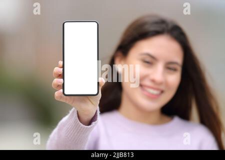 Vorderansicht einer glücklichen Teenager-Frau mit leerem Handybildschirm Stockfoto