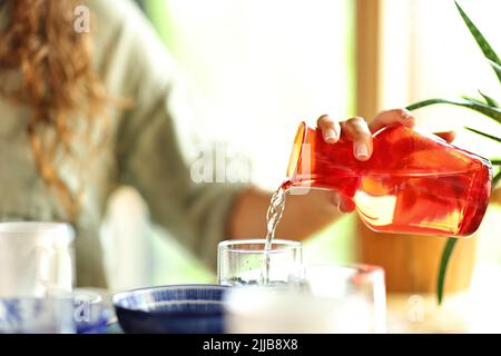 Nahaufnahme eines Porträts einer Frau, die in einem Restaurant Wasser in ein Glas gießt Stockfoto