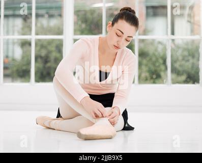 Ich werde heute nicht fallen. Eine schöne junge Ballerina, die sich für das Training in einem Tanzstudio vorbereitet. Stockfoto