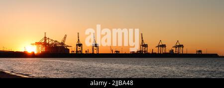 Hafen in Danzig mit Handelsdock und Kränen bei Sonnenuntergang. Panoramablick vom Stogi Strand in der Ostsee. Silhouette des Industriehafens Stockfoto