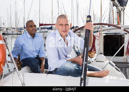 Ein paar Jungs in blauen Hemden plaudern auf einer privaten Segelyacht im Seehafen Stockfoto