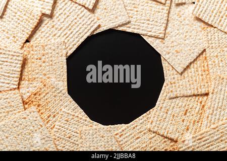 Ein Foto von Matza oder Matza-Stücken auf schwarzem Hintergrund. Matza für die jüdischen Passahfeiertage. Platz für Text, Platz zum Kopieren Stockfoto