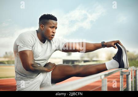 Ein hübscher junger Athlet, der sich vor dem Training im Freien aufwärmt, erwärmt sich. Stockfoto