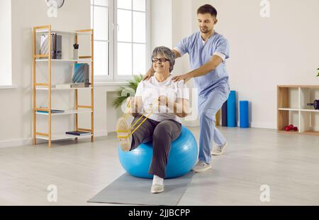 Der professionelle männliche Physiotherapeut arbeitet mit älteren weiblichen Patienten im Rehabilitationszentrum zusammen. Stockfoto