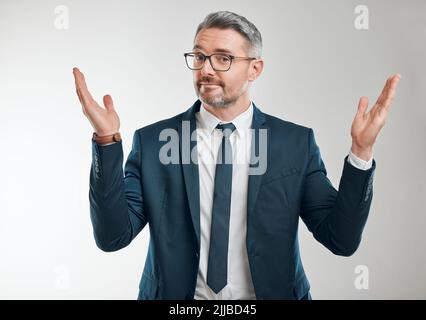 Ich überlasse es Ihnen, eine Entscheidung zu treffen. Studioporträt eines reifen Geschäftsmannes, der vor weißem Hintergrund zuckert. Stockfoto