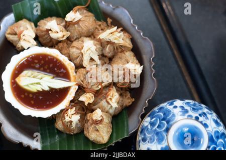 Eine Draufsicht auf eingewickelte Knödel mit einer würzigen Sauce in einer Schüssel Stockfoto
