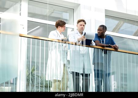 Niedrig-Winkel-Porträt von Medizinern auf dem Balkon der modernen Klinik oder Krankenhaus stehen, Kopierraum Stockfoto