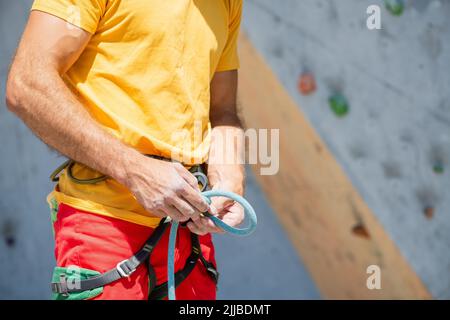 Ein Mann bereitet sich darauf vor, eine Kletterroute zu besteigen. Versicherung und Sicherheit beim Klettern. Sicherheitsseil. Knoten acht. Stockfoto