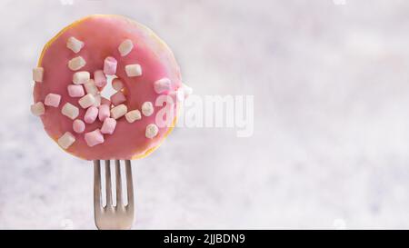 Nahaufnahme der Gabel mit rosa glasierten Donut mit marshmalow .große Donut Hintergrund mit Kopieplatz für Banner Stockfoto