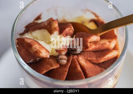 Nahaufnahme des klassischen Tiramisu-Kuchens in einem Glas auf Betongrund. Detail der mehrlagigen Mascarpone Dessertkuchen. Stockfoto