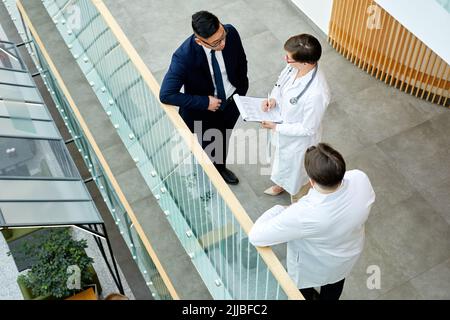 Grafische Ansicht von oben nach unten auf dem Balkon einer modernen Klinik, in der Ärzte über den Fall sprechen Stockfoto