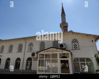 Gebäude mit weißer Fassade und Bogenfenstern und Minarett unter klarem blauem Himmel Stockfoto