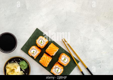Sushi-Brötchen mit Öko-Lachs, serviert auf einem grünen Pappenteller, Blick von oben Stockfoto