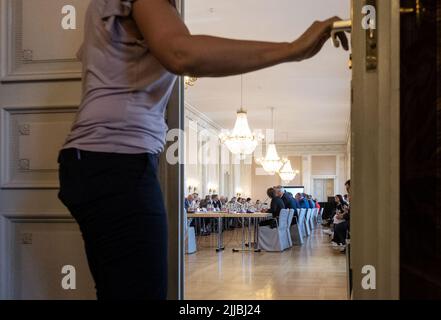 Stuttgart, Deutschland. 25.. Juli 2022. Eine Frau schließt die Tür zur Veranstaltungshalle am Gasgipfel der grün-schwarzen Staatsregierung im Neuen Palast. Der baden-württembergische Ministerpräsident Kretschmann hatte Vertreter aus Wirtschaft, Gewerkschaften, Kommunen und Versorgungsunternehmen in das Neue Schloss eingeladen, um sich auf einen möglichen Engpass im Herbst und Winter vorzubereiten. Quelle: Marijan Murat/dpa/Alamy Live News Stockfoto