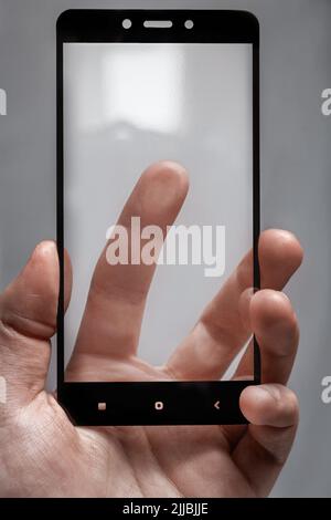 Schutzglas für das Telefon in männlicher Hand und Finger, die die Bildschirmoberfläche berühren. Stockfoto