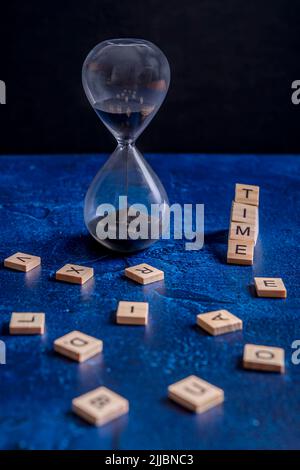 Eine Sanduhr mit schwarzem Sand und dem Wort 'Zeit' daneben Stockfoto