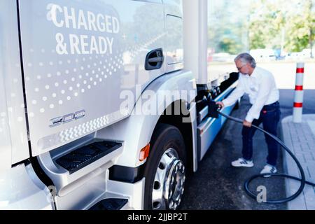 25. Juli 2022, Rheinland-Pfalz, Wörth am Rhein: Ein Mitarbeiter demonstriert bei der Eröffnung des neuen Netz BW und Daimler Truck Demo-Ladeparks, wie man einen Lkw im Mercedes-Benz Trucks Kundencenter lädt. Im neuen Kunden-Demo-Park können Besucher ab dem 1. August 2022 Ladesäulen und Ladekonzepte für Elektro-Lkw im realen Betrieb testen. Foto: Uwe Anspach/dpa Stockfoto