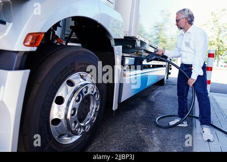 25. Juli 2022, Rheinland-Pfalz, Wörth am Rhein: Ein Mitarbeiter demonstriert bei der Eröffnung des neuen Netz BW und Daimler Truck Demo-Ladeparks, wie man einen Lkw im Mercedes-Benz Trucks Kundencenter lädt. Im neuen Kunden-Demo-Park können Besucher ab dem 1. August 2022 Ladesäulen und Ladekonzepte für Elektro-Lkw im realen Betrieb testen. Foto: Uwe Anspach/dpa Stockfoto