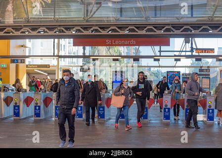 Menschen, einige mit Masken, die ihre Opalkarte benutzten, um an einem Wintermorgen in Sydney, Australien, durch die Swipe-Tickettore an der St. Leonards Station zu gelangen Stockfoto