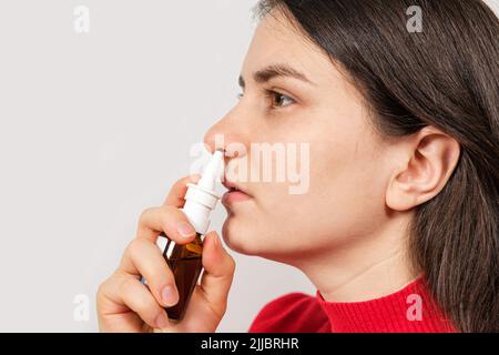 Eine Patientin schiebt ein Spray in die Nase, um Rhinitis, eine Allergie mit Atembeschwerden, zu behandeln. Textbereich kopieren. Stockfoto