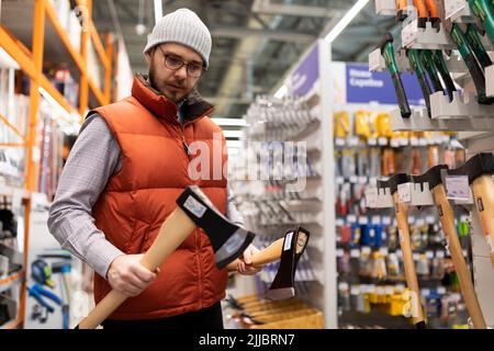 Ein Mann in einem Baumarkt wählt eine Hausaxt Stockfoto