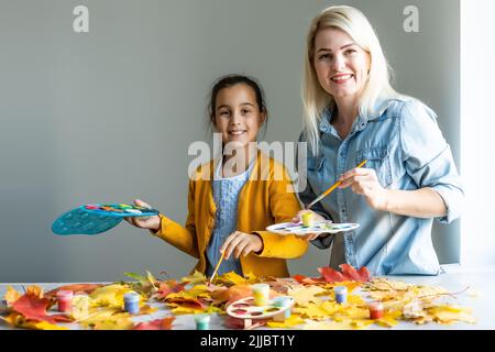 Mutter und Tochter malen Herbstblätter Stockfoto