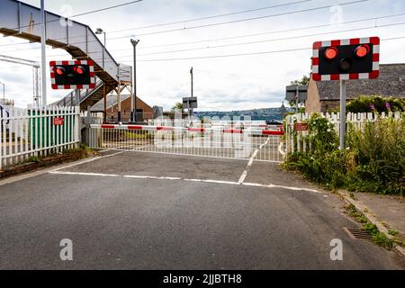 Vollständige Barriere abwärts, öffentlicher Highway manuell gesteuerte Barrieren (lokal überwacht durch CCTV) über den Bahnübergang mit roten Warnleuchten Stockfoto