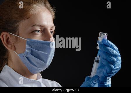 Eine Ärztin zieht einen Impfstoff oder ein Medikament in eine Spritze. Die Krankenschwester zieht den Impfstoff, die Grippemedikamente und Krankheiten in die Spritze Stockfoto