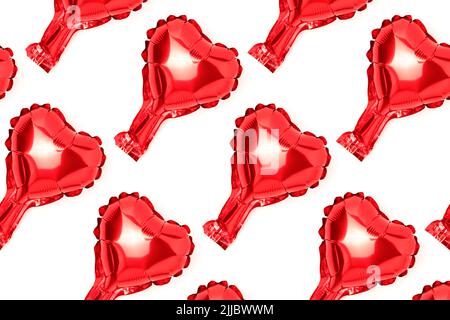 Repetitives Muster aus rotem Herz-Folienballon. Kreatives Layout auf weißem Hintergrund. Stockfoto