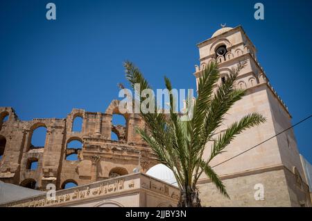 Das Minarett der Großen Moschee von El Jem befindet sich außerhalb der riesigen Ruinen des antiken römischen Amphitheaters. Stockfoto