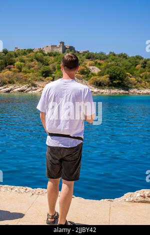 Mann von hinten denkt und schaut in die Nähe des Schlosses Stockfoto