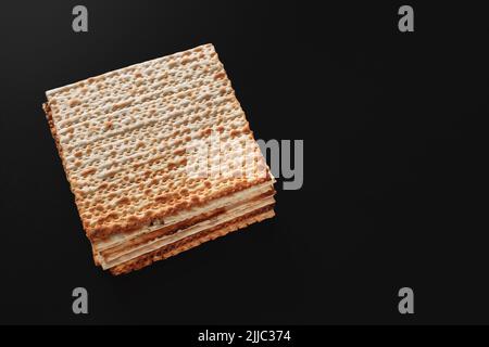 Ein Foto von Matza oder Matza-Stücken auf schwarzem Hintergrund. Matza für die jüdischen Passahfeiertage. Platz für Text, Platz zum Kopieren Stockfoto