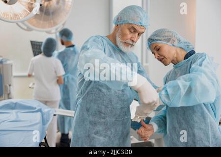 Team von Chirurgen im Operationssaal, die sich auf die Operation vorbereiten Stockfoto