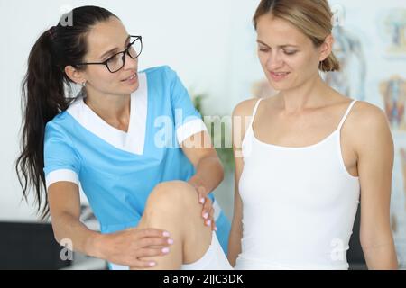 Weibliche Patientin, die nach einer Beinverletzung im Rehabilitationszentrum medizinisch versorgt wird Stockfoto