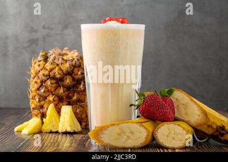 Bananen-, Erdbeer- und Ananas-Smoothie auf dem Holztisch und Bubble Tea oder boba-Teebällchen darauf Stockfoto