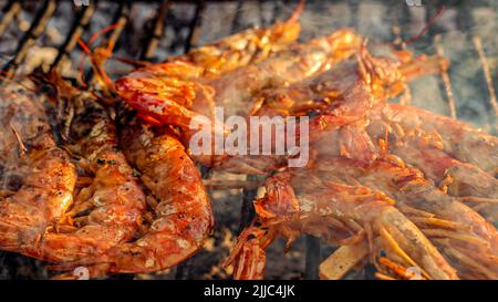 Gegrillte Garnelen auf einem Grill mit Holzkohlegrill. Nahaufnahme von Garnelen, die in der Ölpfanne gebraten werden Stockfoto