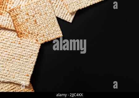 Ein Foto von Matza oder Matza-Stücken auf schwarzem Hintergrund. Matza für die jüdischen Passahfeiertage. Platz für Text, Platz zum Kopieren Stockfoto