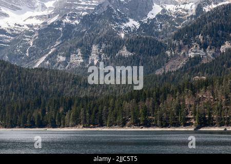 Winziger alpiner See von Tovel, umgeben von uralten Tannen und Felsen, bedeckt mit ewigem Schnee, Ville d'Anaunia, Trentino, Italien Stockfoto