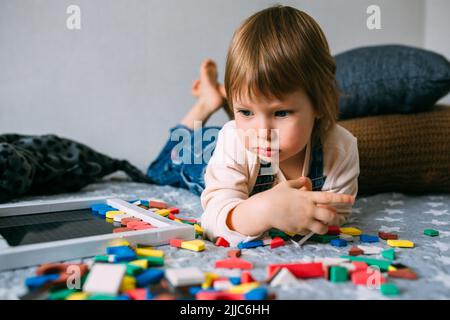 Kind spielt zu Hause ein lehrreiches Spiel mit einem mehrfarbigen magnetischen Puzzle Stockfoto