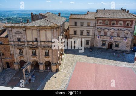 Erhöhter Blick auf mittelalterliche Paläste und Brunnen auf der Piazza Grande vom Turm des Palazzo Comunale in der Hügelstadt Montepulciano in der Toskana, Italien Stockfoto