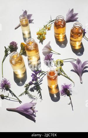 Auswahl an ätherischen Ölen, mit Kräutern und Blumen auf weißem Hintergrund. Draufsicht Stockfoto