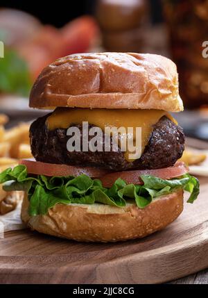 Nahaufnahme von Cheeseburger mit Salat und Tomaten auf einer Holzplatte Stockfoto