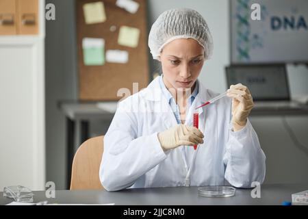 Porträt einer Laborantin, die Experimente mit roter Flüssigkeit im Reagenzglas durchführt, Kopierraum Stockfoto