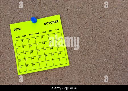 Oktober 2023 gelber Haftnotizkalender mit Pin auf Kork-Bulletin-Plakatwand. Stockfoto