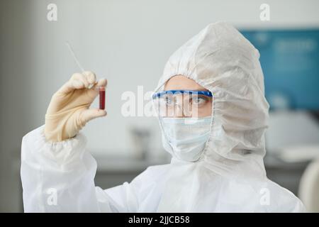 Seitenansicht Porträt von zwei Personen, die eine vollständige Schutzausrüstung tragen und Blutproben im medizinischen Labor analysieren Stockfoto