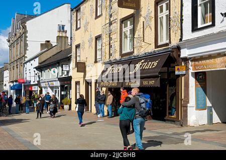 Geschäfte Geschäfte Geschäfte Menschen Touristen Besucher Spaziergänger im Stadtzentrum Spring Winter Market Square Keswick Cumbria Lake District England Vereinigtes Königreich Stockfoto