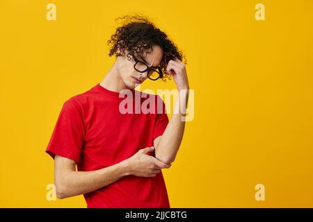 Nachdenklich nachdenkliche myopische junge Student Mann in roten T-Shirt lustige Brille posiert isoliert auf über gelben Studio-Hintergrund. Das beste Angebot mit gratis Stockfoto