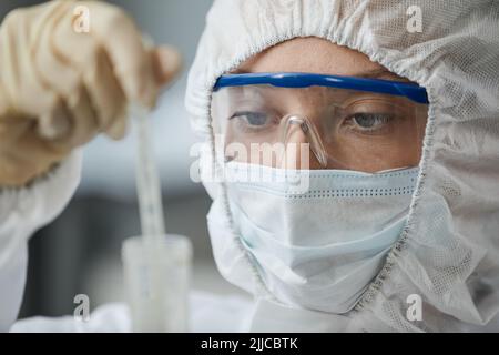 Seitenansicht Porträt von zwei Wissenschaftlerinnen, die in voller Schutzkleidung unterwegs sind, während sie im medizinischen Labor mit gefährlichen Materialien forschen Stockfoto