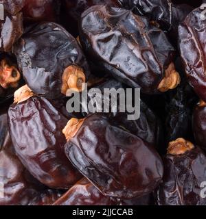 Haufen frischer Datteln, Nahaufnahme von essbaren und tropischen süßen Früchten, Hintergrund von oben, Makro Stockfoto