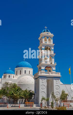 Griechischer Kirchturm, Timiou Stavro in Perissa auf Santorini, im Hintergrund die Kirche des Heiligen Kreuzes, vertikal Stockfoto